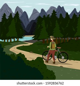 A man with a bicycle goes along a path in the forest with a mountain landscape on the horizon. Travel to wild and protected places.
