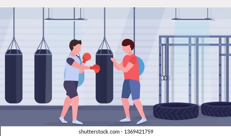 man boxer with personal trainer hitting punching bag in red boxing gloves guy fighter training workout modern fight club gym interior healthy lifestyle concept flat horizontal