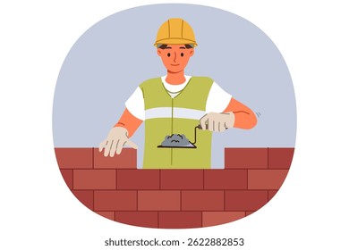 Man bricklayer builder builds brick wall using trowel with concrete mixture to secure blocks. Guy bricklayer in yellow vest and hardhat works in architectural company performing contract work
