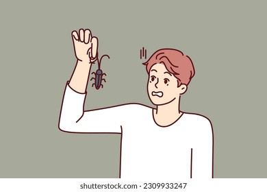 Man with bug in hand, looks at insect and gets scared suffering from arachnophobia and disgust. Guy found bug and wants to get rid of pest by calling service for chemical treatment of insects