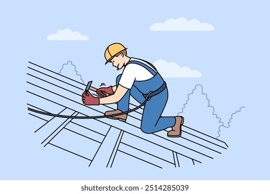 Man builder installs shingles on roof of house, using hammer and nails to securely fasten them. Guy, repair and construction specialist, stands on roof, nailing boards to frame of building.