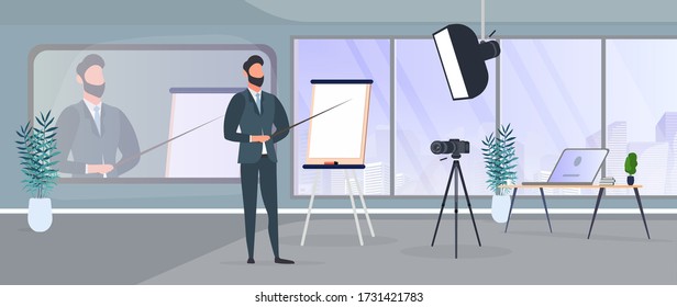 A man in a business suit with a tie is giving a presentation to the camera. The teacher is writing a lesson. The concept of blogging, online training and conferences. Camera on a tripod, softbox. 