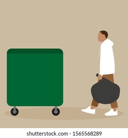 A man carries a bag of garbage to the trash can