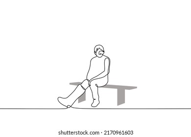 man with a cast on his right leg sadly sits alone on a bench - one line drawing vector. concept an injured athlete sits idle, a man with a broken leg on which a plaster