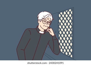 Man catholic priest listens to confession, located in church in room with mesh wall. Elderly christian minister conducts confession procedure, allowing parishioners to remove burden from souls