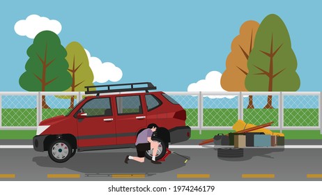A man changes a spare tire on a motorway. Use a jack to pry the car up. Take all the luggage off the car on the side of the road. ฺBackground of steel wire wall separating the grassland and blue sky. 
