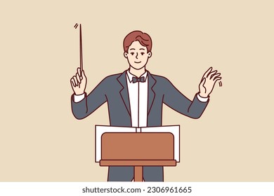 Man conductor participates in acoustic concert and helps orchestra perform classical symphony for audience of performance. Conductor in formal suit and bow tie coordinates musicians from opera house