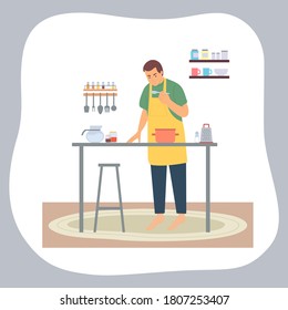 Man cooking at home. Guy wearing apron eat from spoon, looking at pan at table. Male chef preparing food at kitchen, dinner or lunch. Quarantine isolation at home. New hobby. Stay home concept