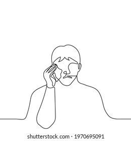 man crying and wiping his tears with a handkerchief - one line drawing vector. concept of sobbing alone, mourning grief
