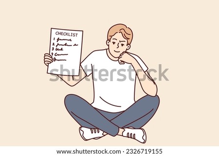 Man demonstrates checklist recommending time management and organizing own work. Smart smiling guy is sitting and holding checklist with tasks for day or step-by-step plan to achieve goal in hand