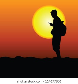 man in the desert looking at mobile on the sunshine