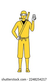 A man dressed up as a ninja using a smartphone at work.