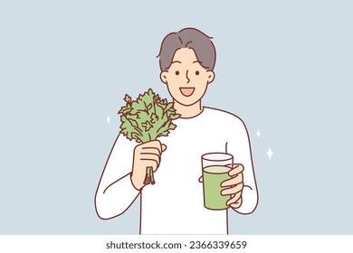 Man drinks celery smoothie following healthy diet to get rid of toxins and excess weight. Happy guy is holding glass with cocktail or smoothie made on basis of organic herbs and plants.