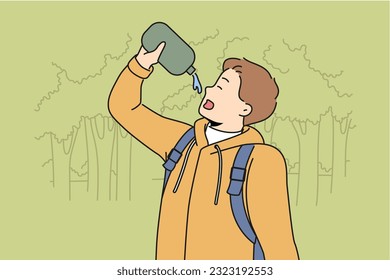 Man drinks water hiking in forest feeling thirsty after long walk through wilderness area with trees. Young guy with flask is fond of hiking and travels in national nature reserve.