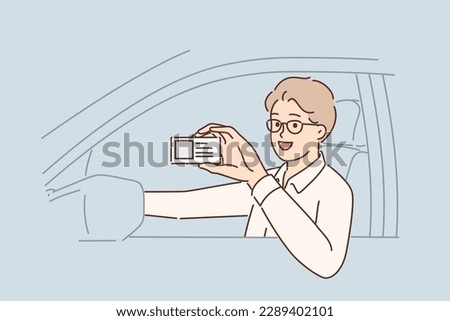 Man driving car demonstrates driver license giving right to work in taxi company. Guy boasts of driver license obtained after studying at driving school and successfully passing exam