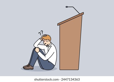 Man experiences peiraphobia, which causes fear speaking in front of audience, and sits near empty podium with microphone. Problem peiraphobia in person with no experience in conducting business events