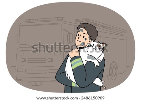 Man firefighter with cat heroically rescued from burning house stands near fire truck and hugs pet. Brave guy in uniform of firefighter or rescue worker helped cat get out of trouble