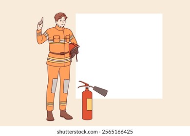 Man firefighter stands near fire extinguisher and copy of space for safety advice. Young guy firefighter from 911 service recommends being careful with electrical equipment and flammable materials