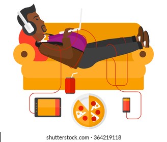 Man with gadgets lying on sofa.