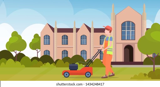 man gardener in uniform cutting grass with lawn mower gardening concept front yard university building exterior flat full length horizontal