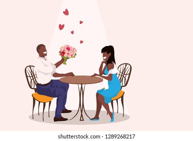 man giving woman flowers bouquet happy valentines day holiday concept african american man woman sitting at table romantic date relationships horizontal flat