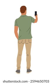 A man in a green shirt and tan pants is taking a picture with his cell phone. Concept of casualness and leisure, as the man is simply enjoying a moment and capturing it with his phone