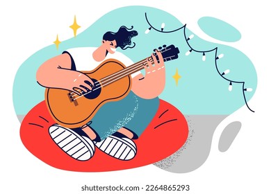 Man guitarist sits in chair with legs folded and plays guitar inventing own music and wishes to become professional singer. Guy learns to play guitar to surprise girl and dedicate serenade to her 