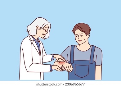 Man with hand injury goes to doctor for help for treatment or for advice on rehabilitation. Elderly woman doctor helps guy in uniform to cure injury received during construction work