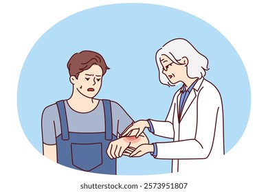 Man with hand injury goes to doctor for help for treatment or for advice on rehabilitation. Elderly woman doctor helps guy in uniform to cure injury received during construction work