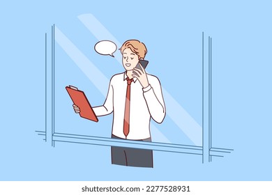 Man head of corporation is talking on phone negotiating with partners, view from behind window skyscraper. Successful guy manager or businessman holding telephone presentation to potential employees 