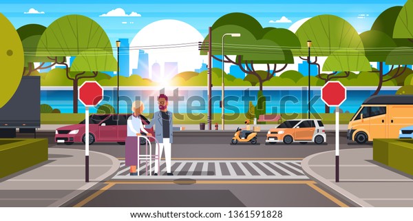 man help senior\
woman with walking stisk crossing street urban city traffic cars on\
road crosswalk river green trees wooden benches cityscape\
background horizontal flat