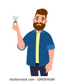 Man is holding broken bulb/damaged bulb. Feeling sad. No idea. Broken light bulb.