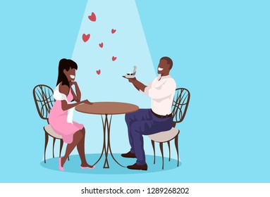 man holding engagement ring proposing to surprised woman marry him happy valentines day concept african couple sitting at table in cafe marriage offer full length horizontal