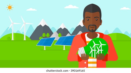 Man holding lightbulb with windmills inside.