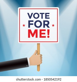 Man holding a placard with VOTE FOR ME message, on a blue background with show lights. Hand holding a square shape promotional banner on a wooden stick. White political candidate promoting himself.