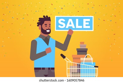 man holding sale banner african american customer with trolley cart full of gift boxes special offer shopping concept flat portrait horizontal vector illustration