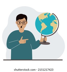 A man holds a globe in his hand and points his finger at it. The concept of education, teacher, world conquest, ecology.