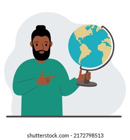 A man holds a globe in his hand and points his finger at it. The concept of education, teacher, world conquest, ecology.