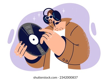 Man holds vinyl record and listens to rare music on headphones, rejoicing at appearance of new audio recordings in collection. Guy with vinyl record to run compositions through phonograph