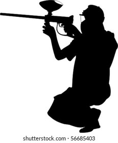 man kneeling while firing a paintball gun