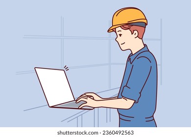 Man with laptop works as engineer in factory and performs setup of production machines, dressed in uniform and hardhat. System administrator of factory or industrial enterprise uses computer