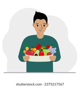 Un hombre con un plato grande de comida orgánica saludable - verduras y frutas. El concepto de alimentación saludable, estilo de vida saludable, vegetarianismo, agricultura.