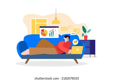 Man Laying on the couch and doing work on a laptop
