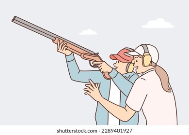 El hombre aprende a sujetar rifles y disparar con armas de fuego bajo la supervisión de una entrenadora. Un atleta profesional con audífonos protectores se dedica a disparar rifles antes de competiciones importantes 