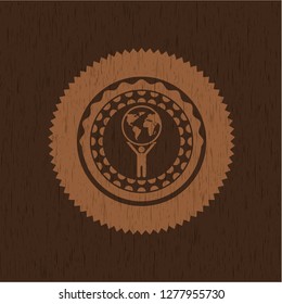 man lifting world icon inside badge with wooden background