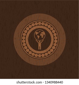 man lifting world icon inside badge with wood background