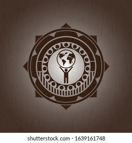 man lifting world icon inside wooden emblem. Vintage.