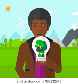 Man with lightbulb and trees inside.