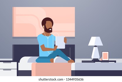 man listening audio book through headphones, african american guy 
