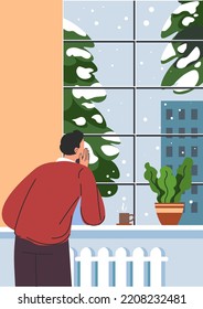 Man looking out of the window, winter season, snowy streets and buildings covered in snow. Male character with a cup of coffee or tea. Home coziness and warms of indoors. Vector in flat style